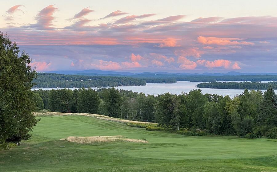 golf green with lake in the background and pink skies overhead