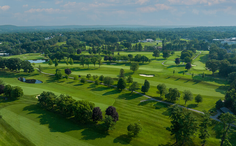 aerial view of golf course with trees, water traps, and sand traps